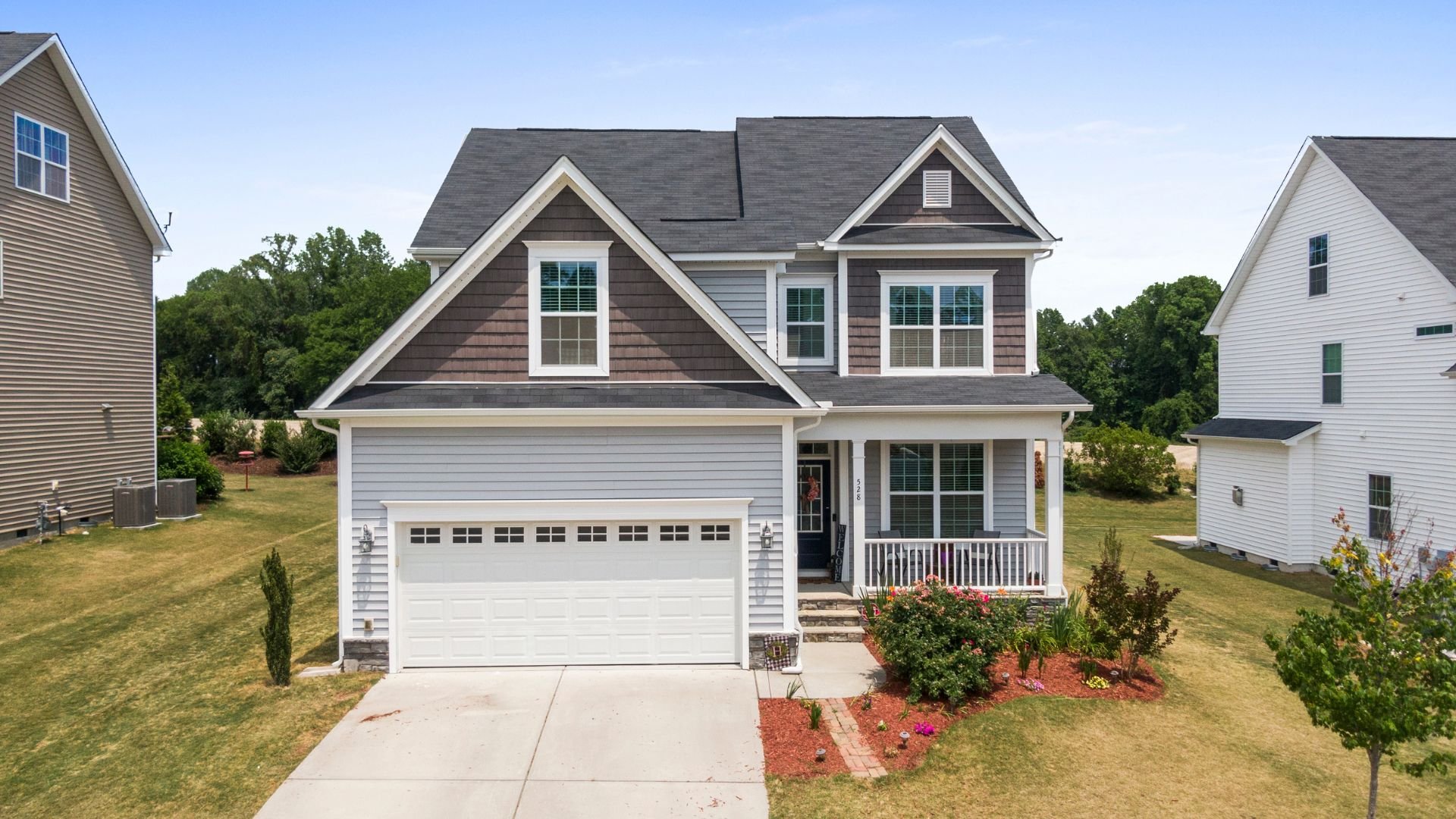 Two-story suburban house with white and brown siding and front yard landscaping