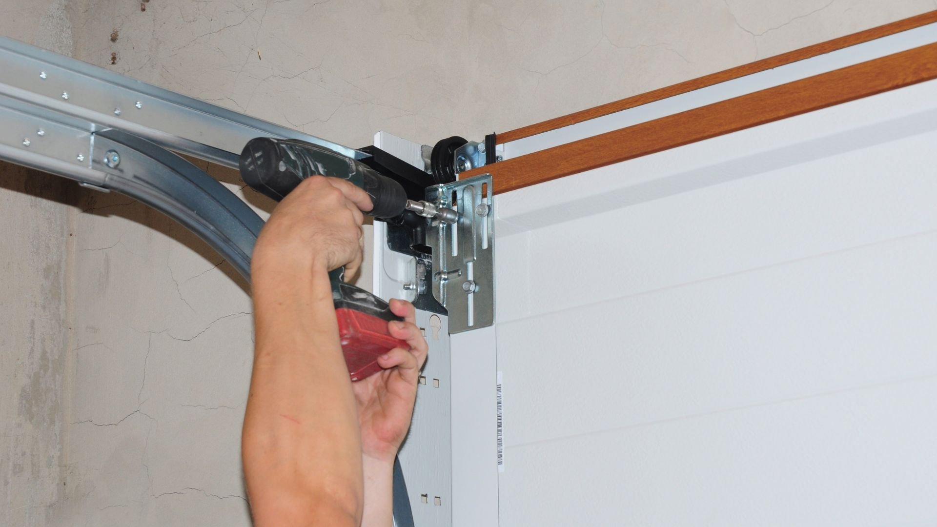 Technician installing or repairing a garage door mechanism with tools
