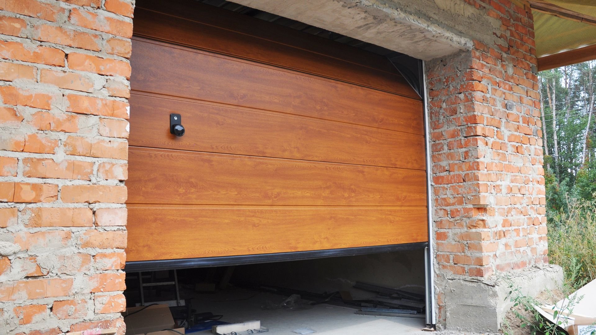 Wooden garage door partially open, set in orange brick wall